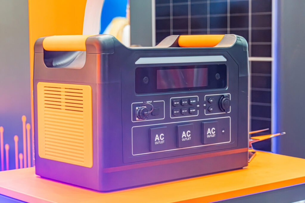 Portable black generator with white labels on an orange surface, control panels, artificial lighting
